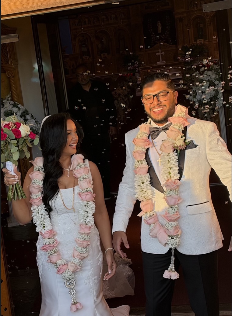 Couple wearing pink floral wedding garlands